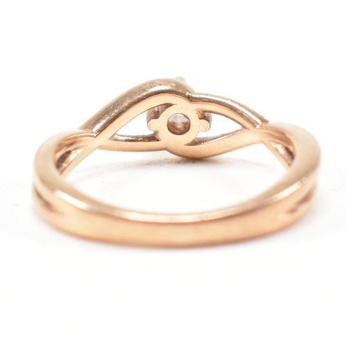 297 - A hallmarked 9ct rose gold and white stone solitaire crossover ring. The single stone engagement sty... 