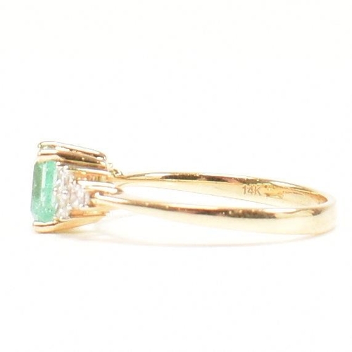 42 - A hallmarked 18ct gold emerald & diamond ring. The ring set with a central emerald flanked by two tr... 