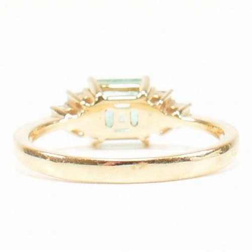 42 - A hallmarked 18ct gold emerald & diamond ring. The ring set with a central emerald flanked by two tr... 