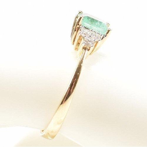 42 - A hallmarked 18ct gold emerald & diamond ring. The ring set with a central emerald flanked by two tr... 