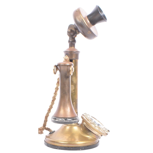 309 - An early 20th century brass candlestick telephone. The telephone of brass construction with black ba... 