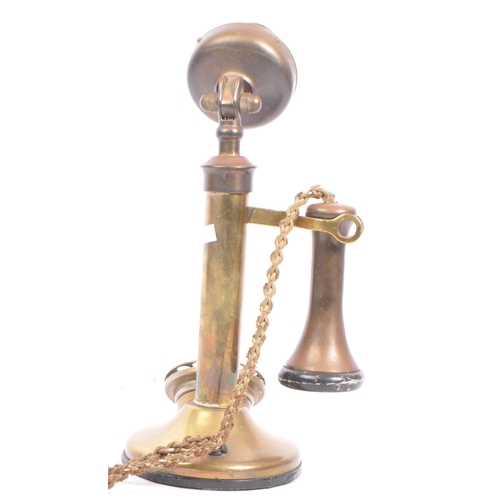 309 - An early 20th century brass candlestick telephone. The telephone of brass construction with black ba... 