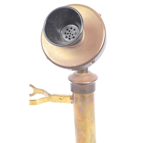 309 - An early 20th century brass candlestick telephone. The telephone of brass construction with black ba... 