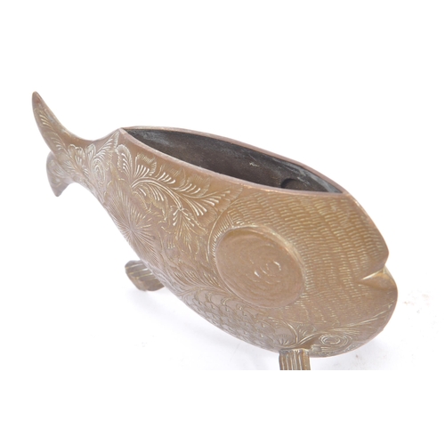 253 - An early 20th century engraved brass fish vase ornament. The fish having a rounded body, raised on f... 