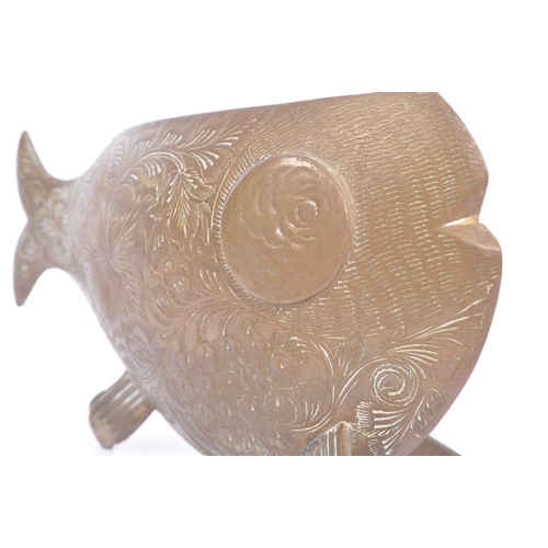 253 - An early 20th century engraved brass fish vase ornament. The fish having a rounded body, raised on f... 