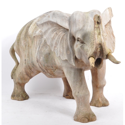 259 - A large proportioned 20th century carved wood elephant. The decoration in the form of a walking elep... 