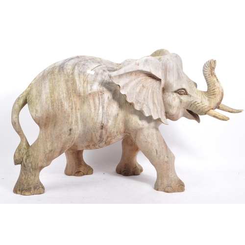 259 - A large proportioned 20th century carved wood elephant. The decoration in the form of a walking elep... 