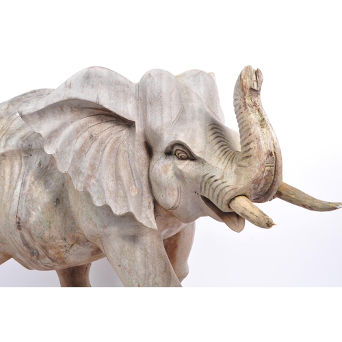 259 - A large proportioned 20th century carved wood elephant. The decoration in the form of a walking elep... 