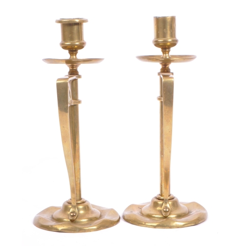 331 - A pair of early 20th century arts & crafts / Art Nouveau brass candlesticks. Having scalloped bases ... 