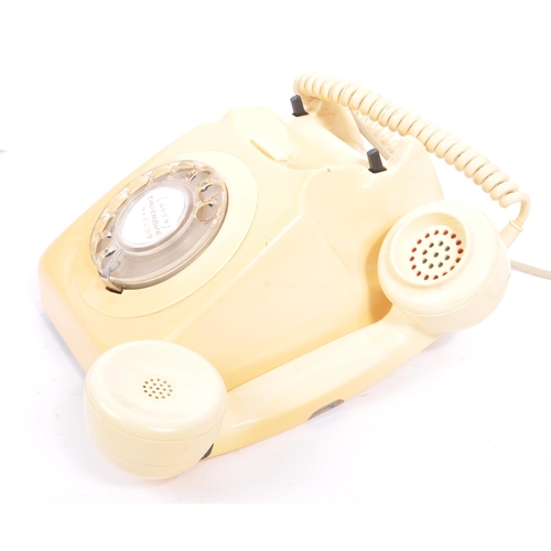 348 - A collection of three mid 20th century rotary dial telephones. The telephones each in a yellow, crea... 