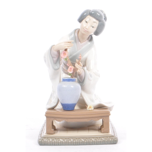 94 - Lladro - A vintage 20th century porcelain china Japanese Geisha figurine. The woman arranging flower... 