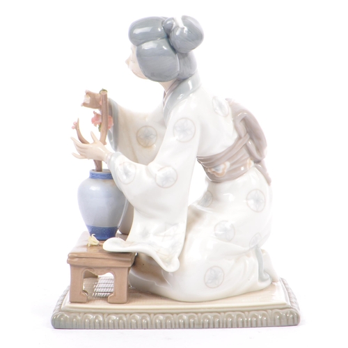 94 - Lladro - A vintage 20th century porcelain china Japanese Geisha figurine. The woman arranging flower... 