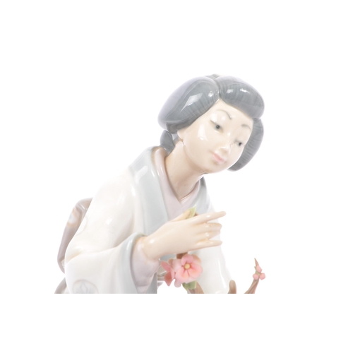 94 - Lladro - A vintage 20th century porcelain china Japanese Geisha figurine. The woman arranging flower... 