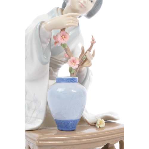 94 - Lladro - A vintage 20th century porcelain china Japanese Geisha figurine. The woman arranging flower... 