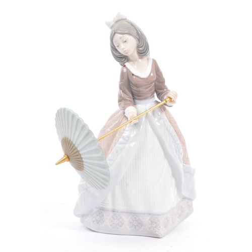 95 - Lladro - Jolie - A porcelain china female figurine. Standing position holding a parasol. Makers mark... 