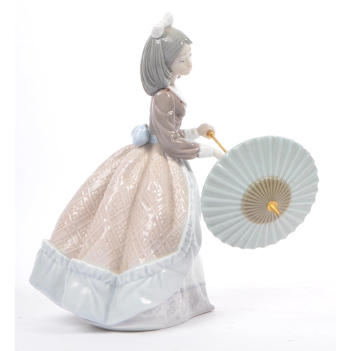 95 - Lladro - Jolie - A porcelain china female figurine. Standing position holding a parasol. Makers mark... 