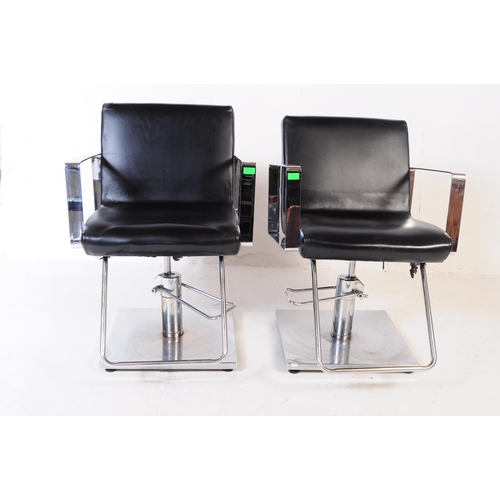 702 - Four contemporary salon barber chairs / adjustable armchairs. The chairs upholstered in black vinyl ... 