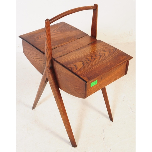 740 - A mid 20th century teak wood sewing box. The sewing box raised on tapered wood legs, with a handle t... 