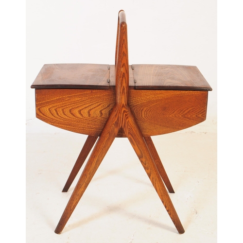 740 - A mid 20th century teak wood sewing box. The sewing box raised on tapered wood legs, with a handle t... 