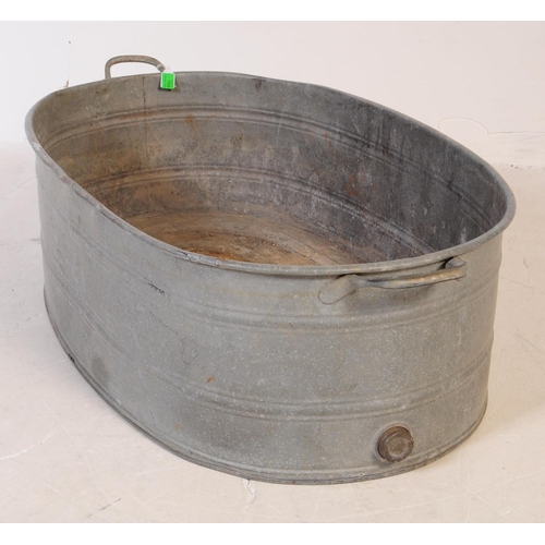 769 - An early 20th century large oval galvanised tin bath. Of oval form, with handles to either side and ... 