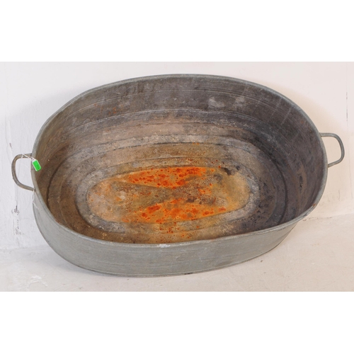 769 - An early 20th century large oval galvanised tin bath. Of oval form, with handles to either side and ... 