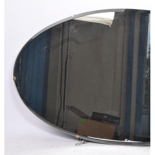 784 - A 1940s mid 20th century frameless oval bevelled edge wall hanging mirror. Having mahogany wood back... 