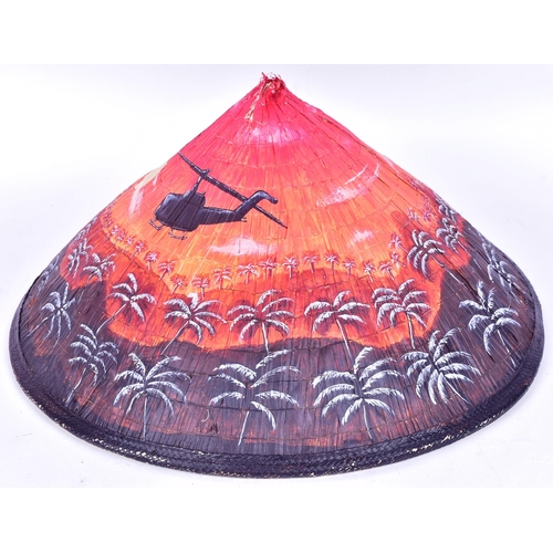 297 - A Vietnam War interest bamboo conical hat with a post war painted scene of two helicopters flying ov... 