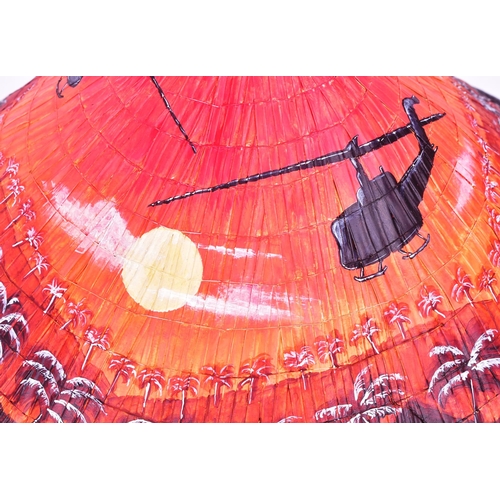 297 - A Vietnam War interest bamboo conical hat with a post war painted scene of two helicopters flying ov... 