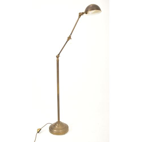 424 - A retro 20th century brassed metal industrial manner floor standard lamp. The light having a dome sh... 