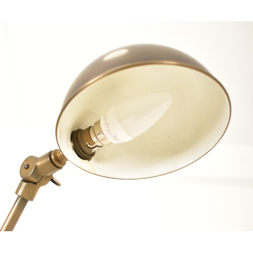 424 - A retro 20th century brassed metal industrial manner floor standard lamp. The light having a dome sh... 