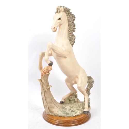 112 - A large resin 20th Century figure of a rearing white horse with a corn to the forefront. The horse s... 