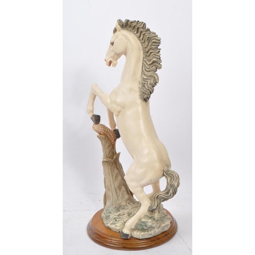 112 - A large resin 20th Century figure of a rearing white horse with a corn to the forefront. The horse s... 