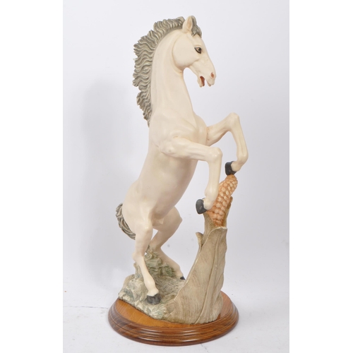 112 - A large resin 20th Century figure of a rearing white horse with a corn to the forefront. The horse s... 