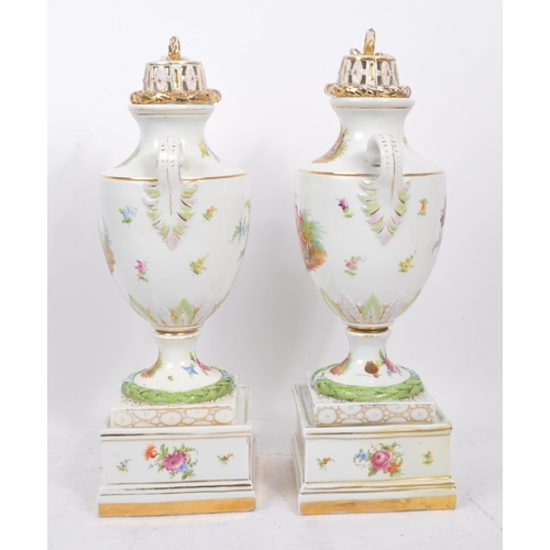 122 - A pair of china porcelain continental Dresden spray style twin handle lidded urns upon a square form... 