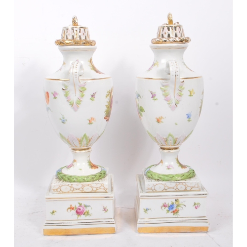 122 - A pair of china porcelain continental Dresden spray style twin handle lidded urns upon a square form... 