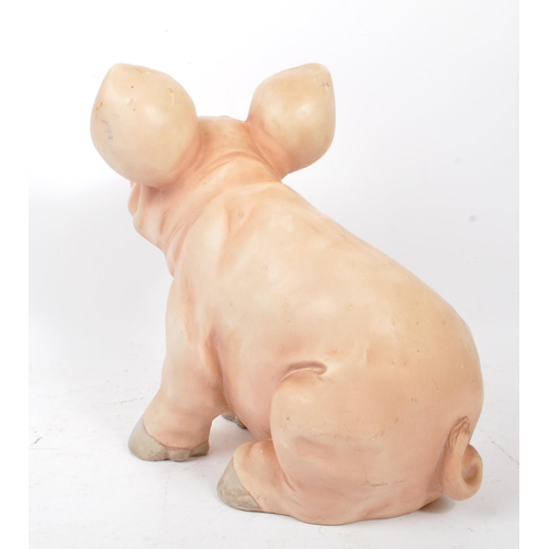 285 - A late 20th century pig swine decorative interior ornament. In a seating position in a pink colourwa... 