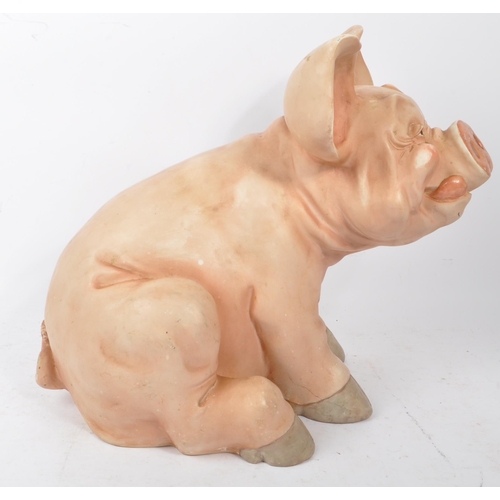 285 - A late 20th century pig swine decorative interior ornament. In a seating position in a pink colourwa... 