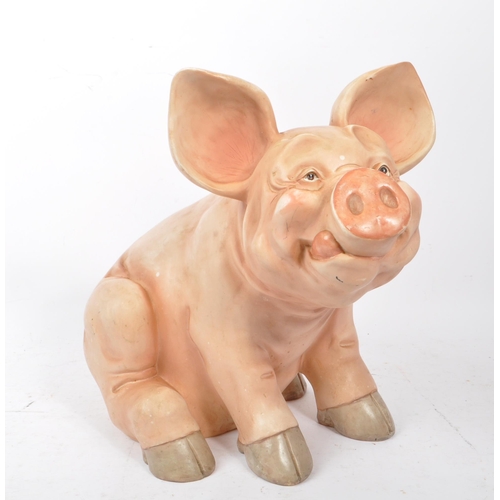 285 - A late 20th century pig swine decorative interior ornament. In a seating position in a pink colourwa... 