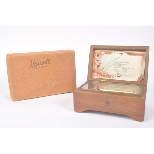 423 - A 20th century Harrods '6 Airs' music box in original box. The music box having a walnut veneer exte... 