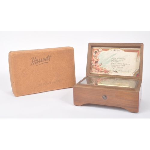 423 - A 20th century Harrods '6 Airs' music box in original box. The music box having a walnut veneer exte... 