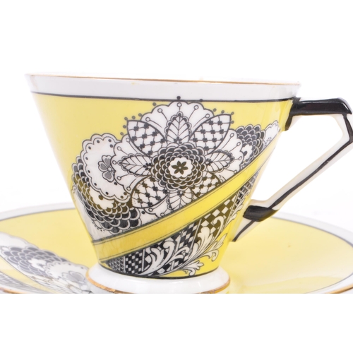 60 - A 1930's china porcelain cup & saucer. With black & white floral geometric decoration to body on a y... 