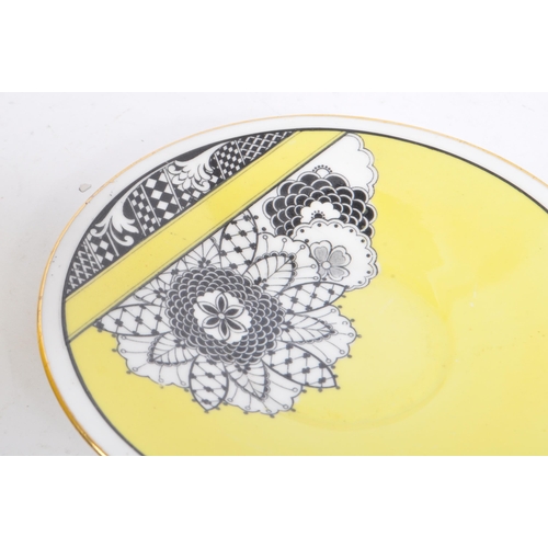 60 - A 1930's china porcelain cup & saucer. With black & white floral geometric decoration to body on a y... 