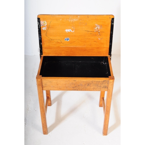 609 - A mid 20th century circa 1940s light oak school desk having hinged top with sliding brass inkwell st... 