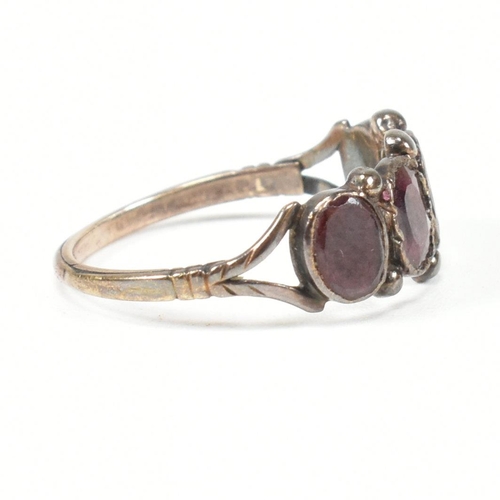 100 - A Georgian gold and garnet four stone ring. The Georgian ring having four bezel set flat cut garnets... 