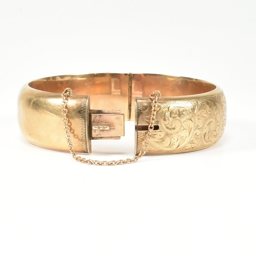 113 - A hallmarked 9ct gold hinged bangle. The gold bangle having bright cut engraved floral decoration to... 