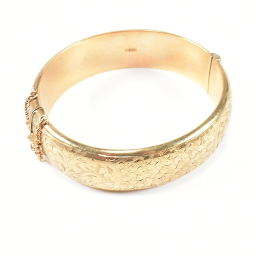 113 - A hallmarked 9ct gold hinged bangle. The gold bangle having bright cut engraved floral decoration to... 