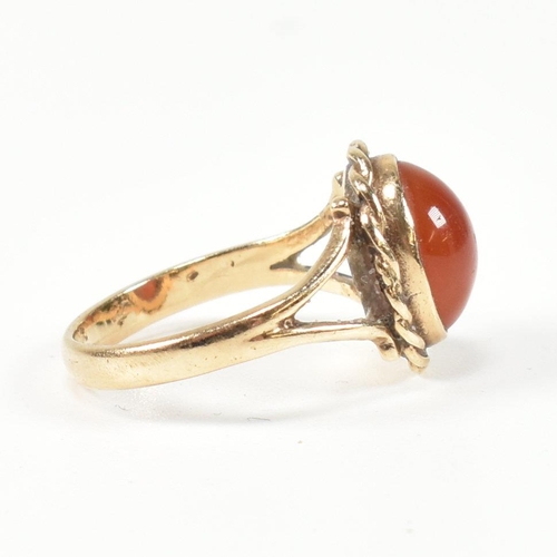 114 - A hallmarked 9ct gold and carnelian ring. The ring set with a carnelian cabochon framed with a rope ... 