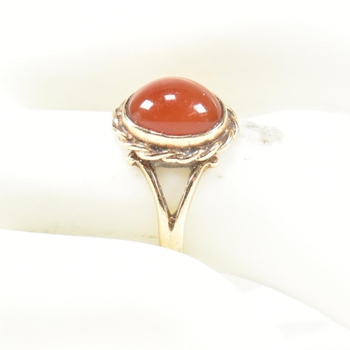 114 - A hallmarked 9ct gold and carnelian ring. The ring set with a carnelian cabochon framed with a rope ... 