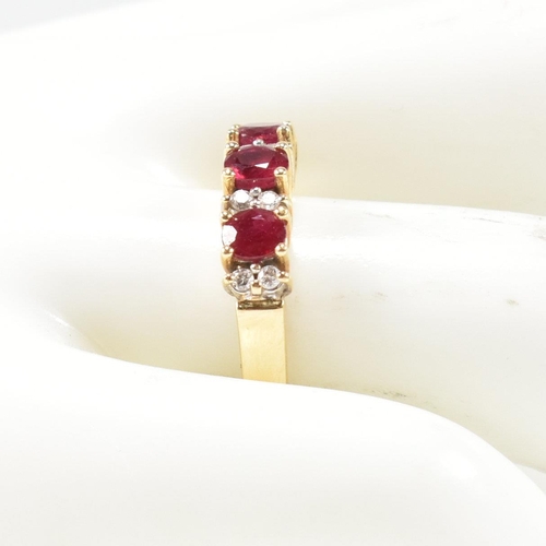 120 - A hallmarked 18ct gold ruby and diamond three stone ring. The ring having three button prong set ova... 