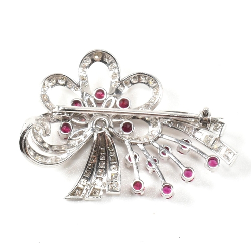 13 - An Art Deco white gold ruby and diamond white spray brooch pin. The brooch set with a central round ... 